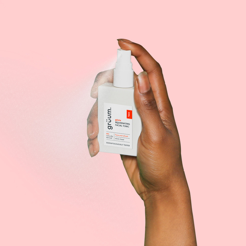 Hand holding facial tonic spray bottle.