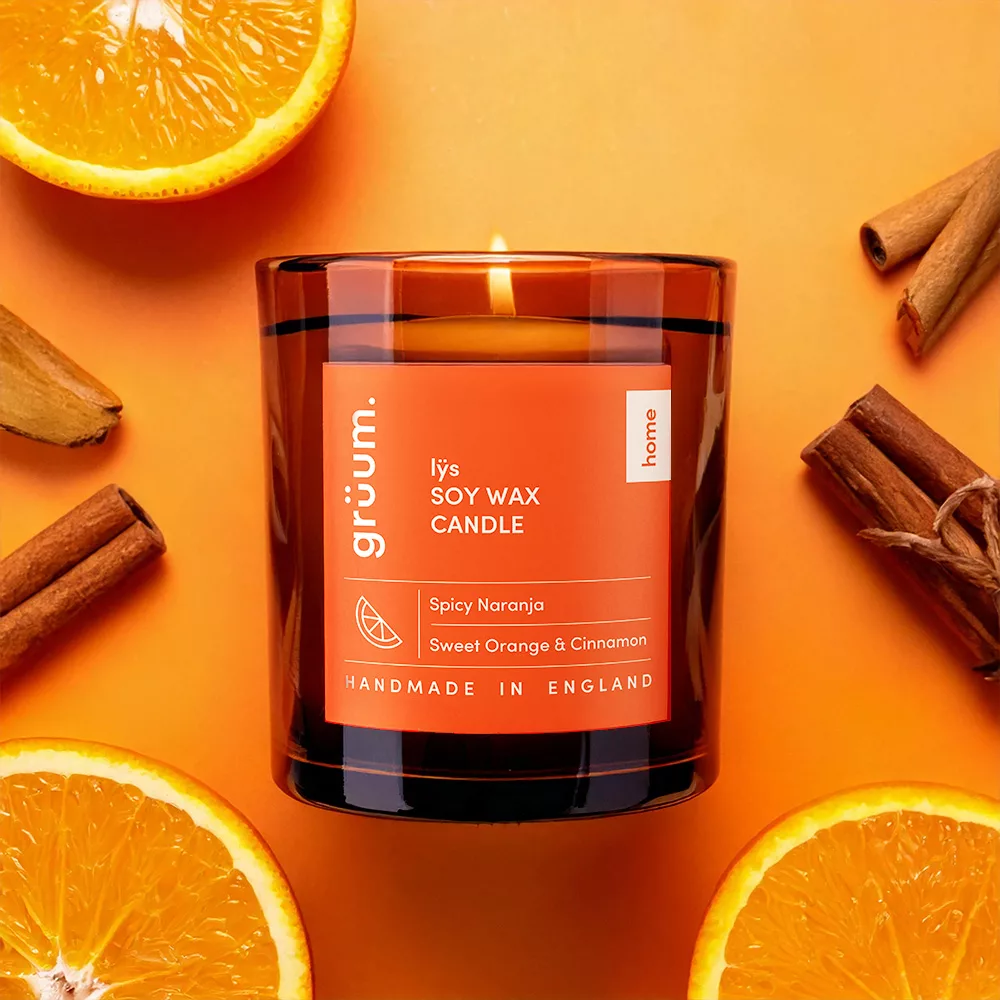 Orange candle with cinnamon and oranges.
