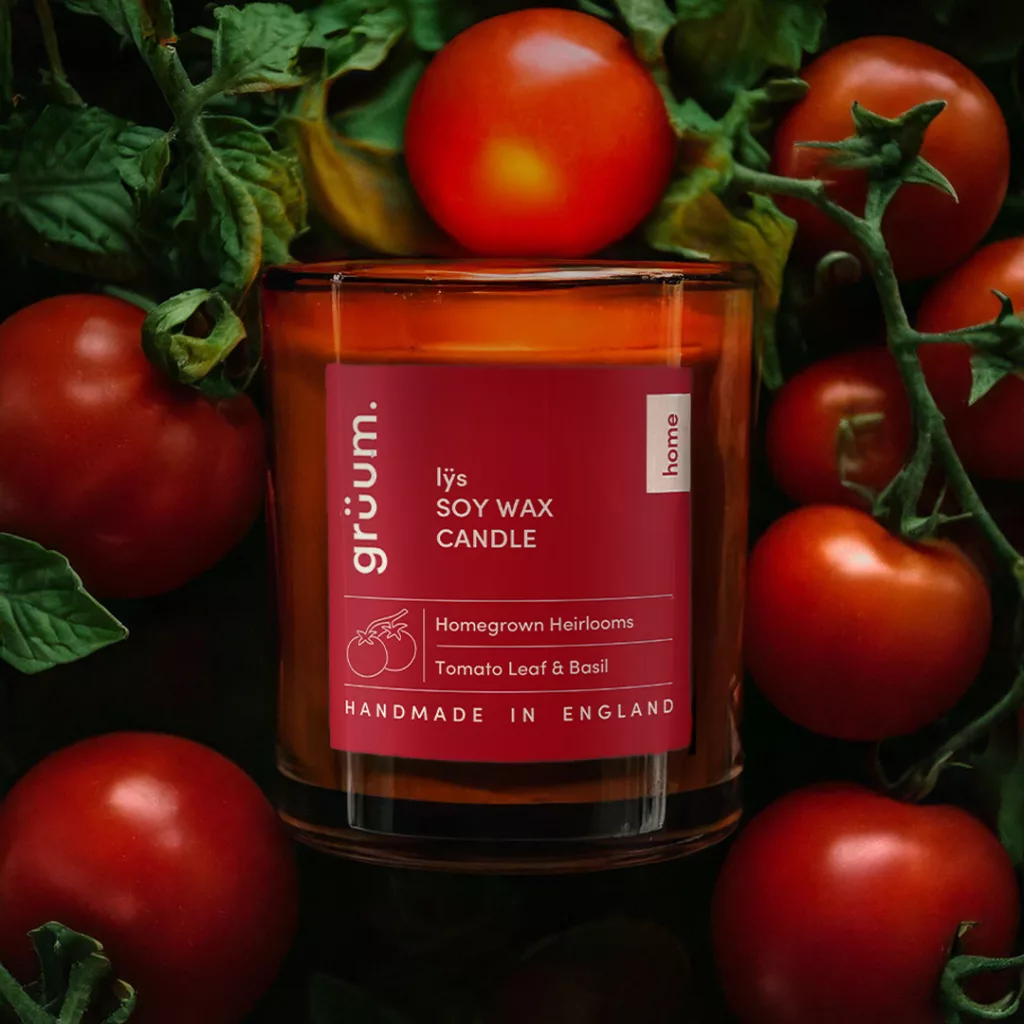 Candle surrounded by tomatoes and leaves.